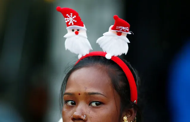 A girl wearing Santa Claus-themed headband sells decorative items ahead of Christmas at a market in New Delhi, India December 19, 2017. (Photo by Adnan Abidi/Reuters)