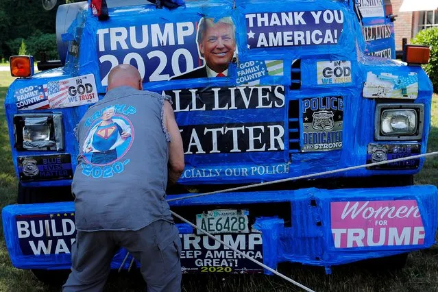 A supporter of U.S. President Donald Trump ties off a banner hanging from a boom during Super Happy Fun America's “Back the Blue/President Trump Standout” in Stoneham, Massachusetts, U.S., July 27, 2020. (Photo by Brian Snyder/Reuters)