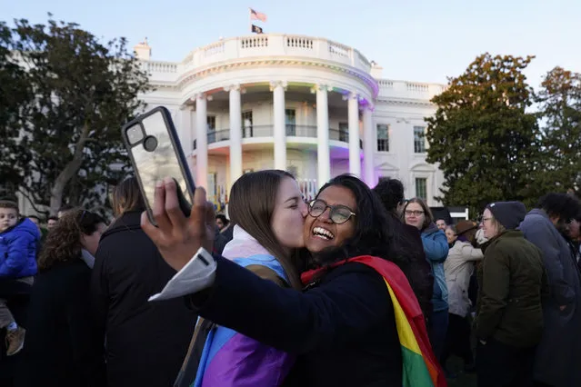 Aparna Shrivastava, right, takes a photo as her partner Shelby Teeter gives her a kiss, after President Joe Biden signed the Respect for Marriage Act, Tuesday, December 13, 2022, on the South Lawn of the White House in Washington. (Photo by Andrew Harnik/AP Photo)