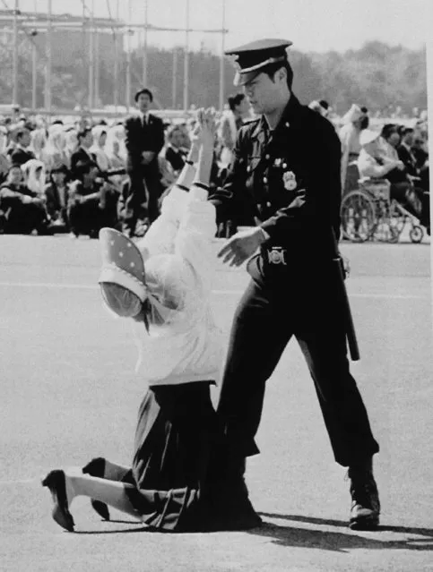 A Seoul policeman attempts to remove a woman who was overcome with emotion during a mass by Pope John Paul II on October 8, 1989 in Seoul's Youido Plaza. An estimated 600,000 people attended the mass. (Photo by Yun Jai-Hyoung/AP Photo)