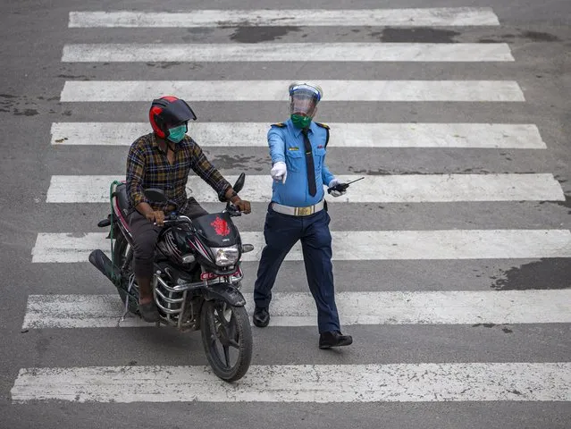 A traffic police officer stops a motorcyclist during lockdown in Kathmandu, Nepal, 26 August 2020. The Kathmandu valley is under a complete lock down, in an effort to combat the spread of coronavirus and COVID-19. (Photo by Narendra Shrestha/EPA/EFE)