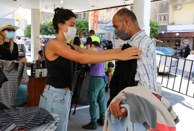 A volunteer helps a man with donated clothes, following the explosion at Beirut port, in Beirut, Lebanon on August 25, 2020. (Photo by Mohamed Azakir/Reuters)