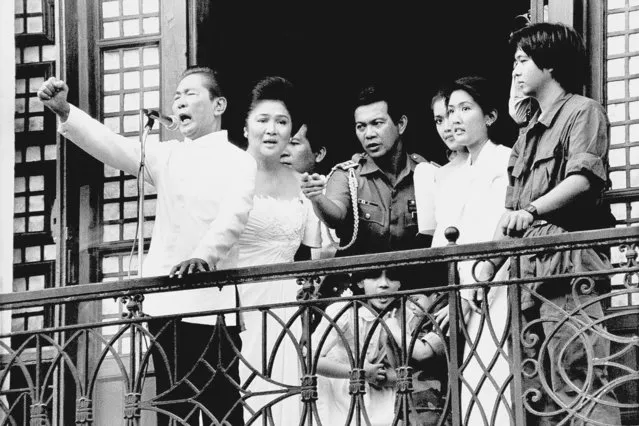 Ferdinand Marcos, with his wife Imelda at his side and Ferdinand Marcos Jr., far right, gestures strongly from the balcony of Malacanang Palace on February 25, 1986 in Manila, just after taking the oath of office as president of the Philippines. Marcos Jr., son of the late dictator and his running mate Sara, who is the daughter of the outgoing President Rodrigo Duterte, are leading pre-election surveys despite his family's history. (Photo by Bullit Marquez/AP Photo/File)