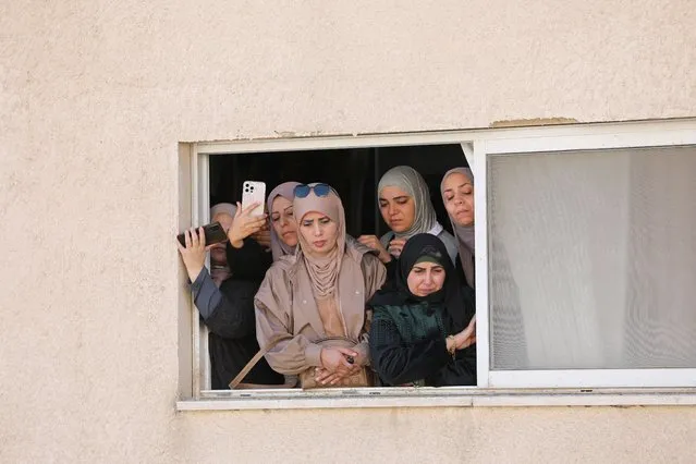 People watch from a window as mourners carry the body of two Palestinians 57-year-old teacher Jawad Bouaqneh and 28-year-old militant Adham Jabbarin during their funeral, in Jenin, in the Israeli-occupied West Bank on January 19, 2023. (Photo by Mohamad Torokman/Reuters)