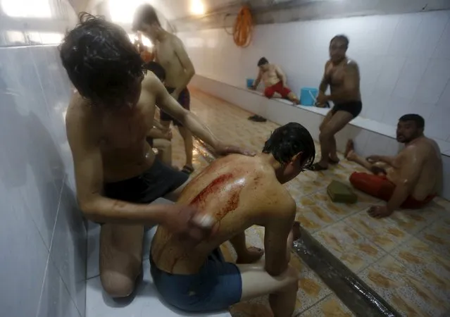 An Afghan Shi'ite Muslim cleans blood from his friend's back in a bathhouse after they flagellated themselves with chains during an Ashura procession in Kabul, Afghanistan October 21, 2015. (Photo by Omar Sobhani/Reuters)