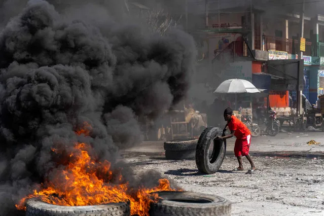 A protestor adds a tire to a burning barricade during a police demonstration to protest the recent killings of six police officers by armed gangs, in Port-au-Prince, Haiti, January 26, 2023. The attacks, which left six officers dead, occurred on January 25 in the town of Liancourt, when officers had to repel four attacks by the gunmen as they tried to take over the station, according to local news. (Photo by Richard Pierrin/AFP Photo)