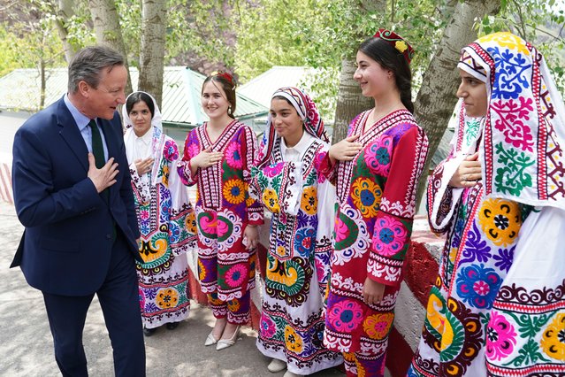 Britain's Foreign Secretary David Cameron (L) is welcomed by a group of women as he arrives at the Nurek Hydro-Electric Project, in the Norak District, on April 22, 2024, as part of a five day tour of the Central Asia region. (Photo by Stefan Rousseau/Pool via AFP Photo)