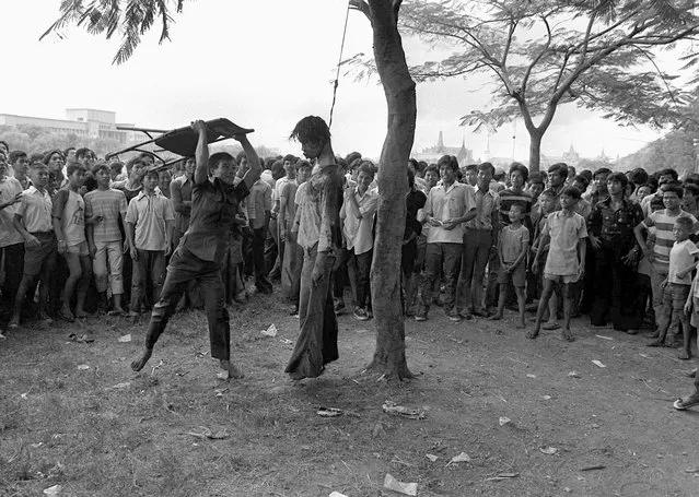 In this October 6, 1976 file photo a member of a Thai political faction strikes at the lifeless body of a hanged student outside Thammasat University in Bangkok Oct. 6, 1976. (Photo by Neal Ulevich/AP Photo)