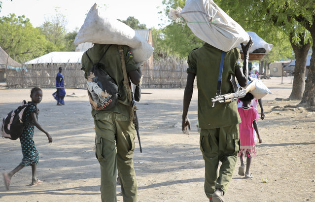 In this photo taken Friday, January 19, 2018, rebel fighters walk through town after receiving food in Akobo, near the Ethiopian border, in South Sudan. (Photo by Sam Mednick/AP Photo)