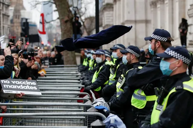 Police officers stand as NHS staff and others protesting against the coronavirus disease (COVID-19) vaccine rules throw NHS uniforms at the entrance to Downing Street in London, Britain, January 22, 2022. (Photo by Peter Nicholls/Reuters)