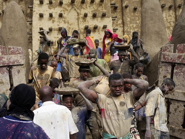Malians take part in the annual replastering of the world's largest mud-brick building, the Great Mosque of Djenne, Mali, Sunday, May 12, 2024. The building has been on UNESCO's World Heritage in Danger list since 2016. The mosque and surrounding town are threatened by conflict. Djenne's mosque requires a new layer of mud each year before the start of the rainy season in June. (Photo by Moustapha Diallo/AP Photo)