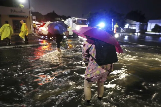 People cross a flooded street in Auckland, Friday, January 27, 2023. Record levels of rainfall pounded New Zealand's largest city, causing widespread disruption. (Photo by Dean Purcell/New Zealand Herald via AP Photo)