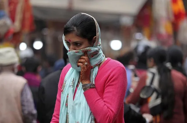 An Indian woman covers her face as a precautionary measure against the coronavirus and walks in a crowded marlet during Diwali, the Hindu festival of lights, in Jammu, India, Saturday, November 14, 2020. (Photo by Channi Anand/AP Photo)