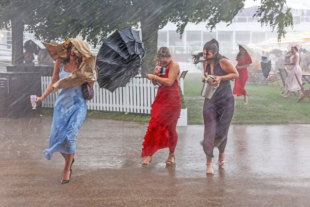 Goodwood racegoers run for cover from a sudden rainstorm on Ladies Day, the third day of the horseracing festival at Goodwood Racecourse on July 31, 2025 in Chichester, England. (Photo by The Times)