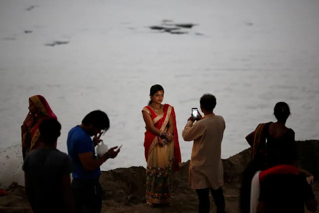 A man takes a picture of his wife in front of the foam covering the polluted Yamuna river in New Delhi, India, October 11, 2016. (Photo by Adnan Abidi/Reuters)