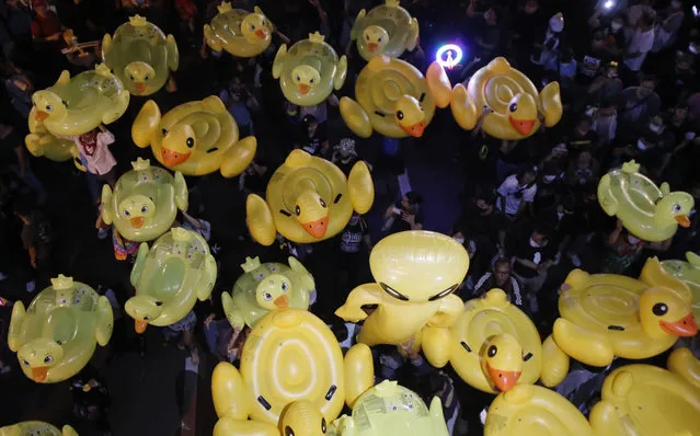 Inflatable yellow ducks, which have become good-humored symbols of resistance during anti-government rallies, are lifted over a crowd of protesters Friday, November 27, 2020 in Bangkok, Thailand. (Photo by Sakchai Lalit/AP Photo)