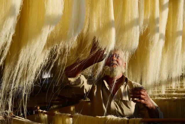 A worker dries vermicelli, which is used to make traditional sweet dishes popularly consumed during the holy month of Ramadan, at a factory in Prayagraj on March 22, 2023. (Photo by Sanjay Kanojia/AFP Photo)