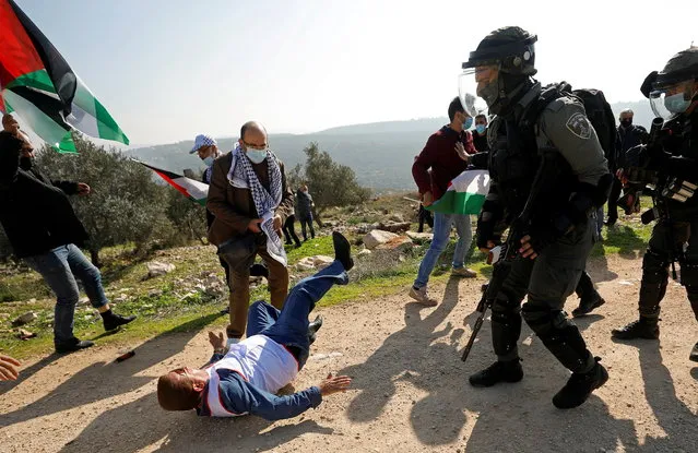 A Palestinian demonstrator falls on the ground after being knocked down by Israeli forces during a protest against Jewish settlements in Salfit in the Israeli-occupied West Bank on December 3, 2020. (Photo by Mohamad Torokman/Reuters)