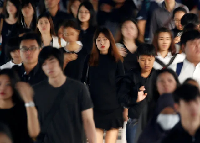 Passengers dressed in black and white or dark coloured clothes, to mourn the passing of Thailand's King Bhumibol Adulyadej, are seen during the morning rush hour at a station in Bangkok, Thailand, October 17, 2016. (Photo by Issei Kato/Reuters)