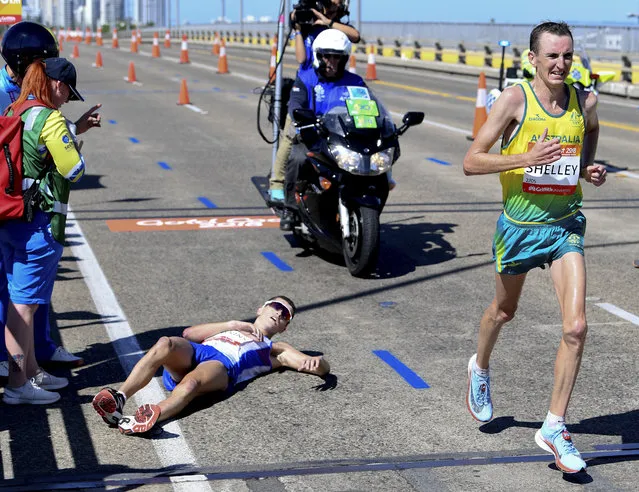 Australia's Michael Shelley, right, passes Callum Hawkins of Scotland after he collapsed during the men's marathon at the XXI Commonwealth Games on the Gold Coast, Australia, Sunday, April 15, 2018. Shelley won the marathon in dramatic fashion when leader Callum Hawkins of Scotland collapsed to the road with cramping with about two kilometers to go. Hawkins had about a two-minute lead over Shelley but became disoriented at about the 38-kilometer mark of the 42.2-kilometer-long race. (Photo by Tracey Nearmy/AAP Image via AP Photo)