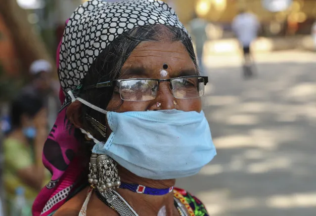 An Indian tribal woman wearing a face mask as a precaution against the coronavirus stands in front of a hospital for a general checkup in Hyderabad, India, Saturday, December 5, 2020. India is second behind the U.S. in total coronavirus cases. Its recovery rate is nearing 94%. (Photo by Mahesh Kumar A./AP Photo)