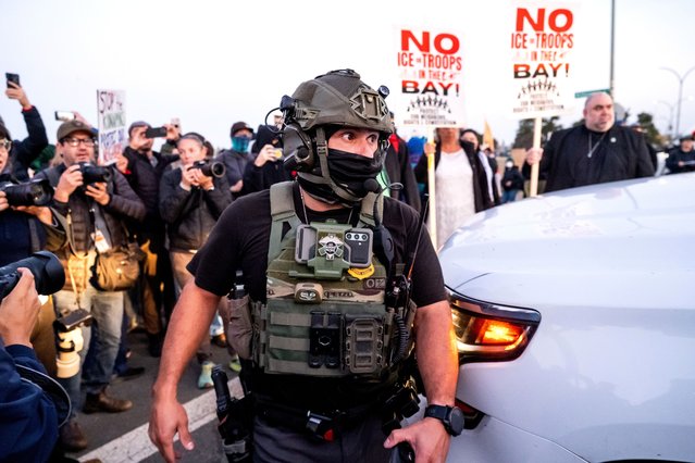 A U.S. Border Patrol officer tries to clear protesters while entering Coast Guard Base Alameda in Oakland, Calif., Thursday, October 23, 2025. (Photo by Noah Berger/AP Photo)