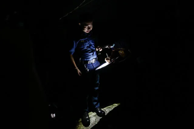 Filipino police investigators write their reports amidst the darkness after a police operation against illegal drugs in Novaliches, Philippines, 25 October 2016. According to police reports, around 2,300 people have been killed in Philippine President Rodrigo Duterte's war against illegal drugs. The figure was revised by the police from an original tally of around 3,600 deaths. (Photo by Mark R. Cristino/EPA)