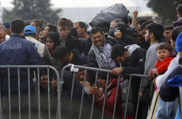 Migrants react in front of a Greek police, as they wait to cross the border from Greece to Gevgelija, Macedonia November 22, 2015. Picture taken from the Macedonian side of the Macedonian-Greek border. (Photo by Ognen Teofilovski/Reuters)