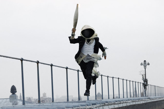 A torchbearer runs atop the Musee d'Orsay during the Opening Ceremony of the Olympic Games Paris 2024 on July 26, 2024 in Paris, France. (Photo by Peter Cziborra/AFP Photo) 