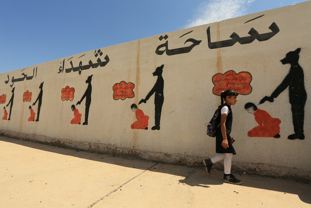 An Iraqi student walks past a school wall covered with drawings showing how Islamic State militants executed their prisoners in Mosul, Iraq on May 08, 2018. (Photo by Ari Jalal/Reuters)