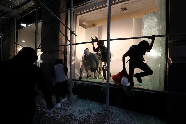 A man jumps from the window of a damaged store as protests against the death in Minneapolis police custody of George Floyd continue, in New York City, U.S., June 2, 2020. (Photo by Jeenah Moon/Reuters)