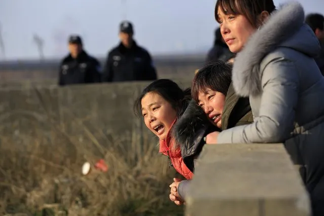 Relatives of a person missing after a tug boat sank, mourn near police officers on the bank of the Yangtze River, near Jingjiang, Jiangsu province January 17, 2015. (Photo by Aly Song/Reuters)