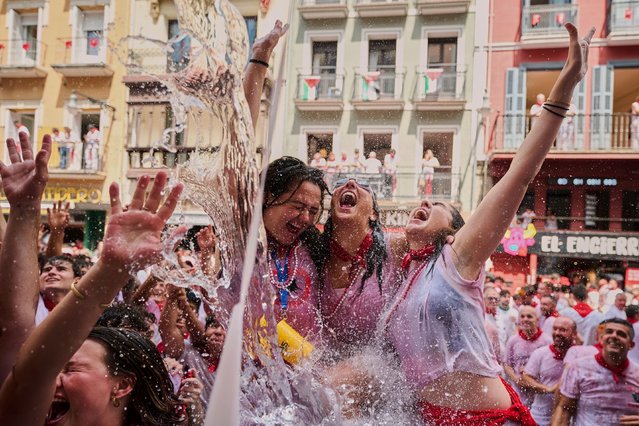 Revelers cool off with water thrown from balconies at the start of nine days of uninterrupted partying during the famed running of the bulls festival in Pamplona, Spain, July 6, 2025. (Photo by Miguel Oses/AP Photo)