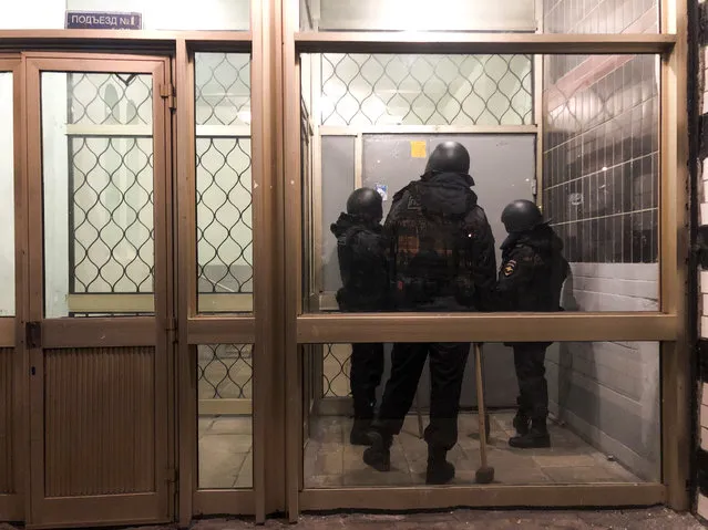 Police stand in front of a door of the apartment building where Oleg Navalny, brother of jailed opposition leader Alexei Navalny lives in Moscow, Russia, Wednesday, January 27, 2021. Police are searching the Moscow apartment of jailed Russian opposition leader Alexei Navalny, another apartment where his wife is living and two offices of his anti-corruption organization. Navalny's aides reported the Wednesday raids on social media. (Photo by Mstyslav Chernov/AP Photo)