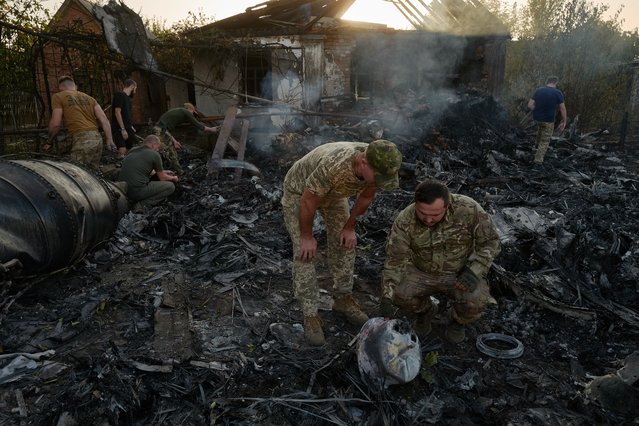 Ukrainian servicemen examine the wreckage of a downed Russian aircraft, likely a Sukhoi S-70 “stealth” heavy unmanned combat aerial vehicle (UCAV), which crashed in a residential area, setting a house on fire on October 5, 2024 in Kostyantynivka, Ukraine. (Photo by Pierre Crom/Getty Images)