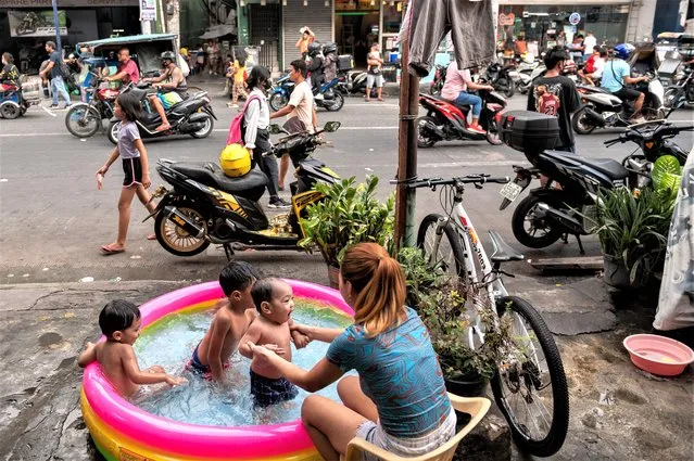 Children play in an inflatable pool beside a street, amid the hot weather during summer, in Manila, Philippines on April 26, 2023. (Photo by Lisa Marie David/Reuters)
