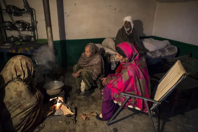 A family sits around a wood fire while waiting for tea to brew at their house on Margalla Hills in Islamabad January 22, 2015. (Photo by Zohra Bensemra/Reuters)