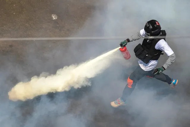 A protester sprays a fire extinguisher as demonstrators clash with riot police officers during a protest against the military coup in Yangon, Myanmar, February 28, 2021. (Photo by Reuters/Stringer)