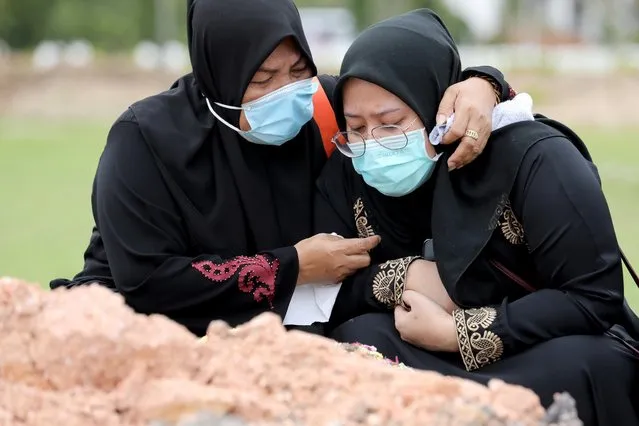 Family members of a victim of the coronavirus disease (COVID-19) cry after a burial at a cemetery, in Batu Caves, Malaysia on January 27, 2021. (Photo by Lim Huey Teng/Reuters)