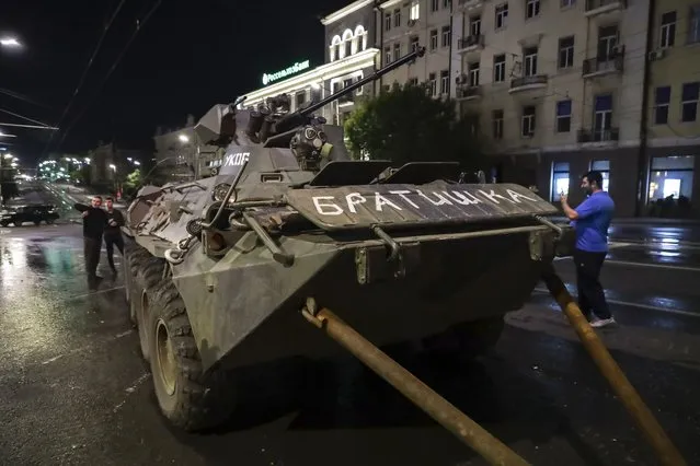 People walk around an armored vehicle of the Wagner Group military company with “Brother” written on it, prior to leaving an area at the headquarters of the Southern Military District on a street in Rostov-on-Don, Russia, Saturday, June 24, 2023. Kremlin spokesman Dmitry Peskov said that Yevgeny Prigozhin's troops who joined him in the uprising will not face prosecution and those who did not will be offered contracts by the Defense Ministry. After the deal was reached Saturday, Prigozhin ordered his troops to halt their march on Moscow and retreat to field camps in Ukraine, where they have been fighting alongside Russian troops. (Photo by AP Photo/Stringer)
