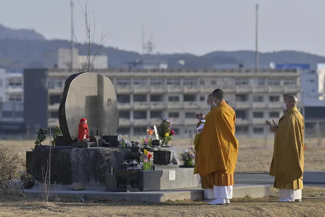 Buddhist monks offer a prayer for victims of the 2011 massive earthquake and tsunami, at a memorial cenotaph near former high school building, background, in Kesennuma, Miyagi prefecture, Japan Thursday, March 11, 2021. Thursday marks the 10th anniversary of the massive earthquake, tsunami and nuclear disaster that struck Japan's northeastern coast. (Photo by Yohei Nishimura/Kyodo News via AP Photo)