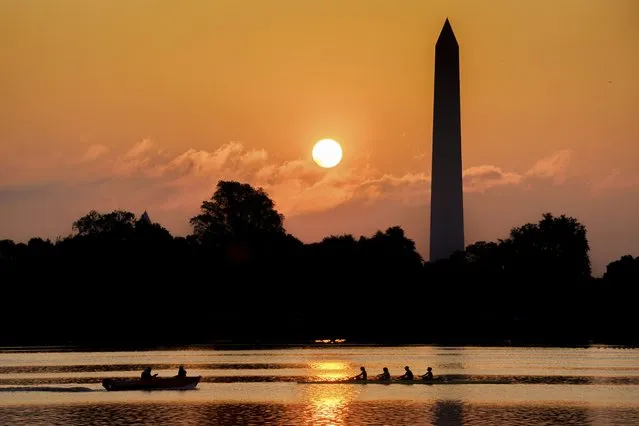 A rowing team glides along the Potomac River past the Washington Monument as the sun rises on another hot and humid day in Washington, Thursday, July 20, 2023. (Photo by J. David Ake/AP Photo)