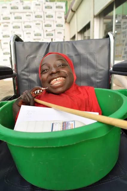 A physically challenged girl smiles she is kept in a basin on her wheelchair to seek alms from people on the street in Kano, Nigeria December 30, 2015. (Photo by Reuters/Stringer)