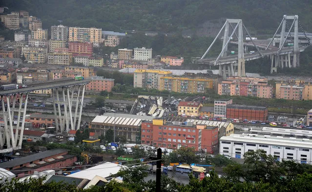 The collapsed Morandi Bridge is seen in the Italian port city of Genoa August 14, 2018. At least 22 people are believed to have died as a large section of the Morandi viaduct upon which the A10 motorway runs collapsed in Genoa on Tuesday. Both sides of the highway fell. Around 10 vehicles are involved in the collapse, rescue sources said. The viaduct gave way amid torrential rain. (Photo by Reuters/Stringer)