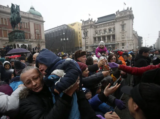 People  gather to receive a piece of traditional Christmas bread to mark the Orthodox Christmas Day festivities in Belgrade, Serbia, Wednesday, January 7, 2016. (Photo by Darko Vojinovic/AP Photo)