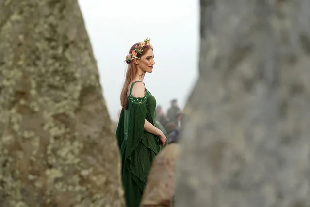 A woman dressed in pagan attire watches the sun rise during the Summer Solstice festivities at Stonehenge in Wiltshire, England, Tuesday, June 21, 2022. After two years of closure due to the COVID-19 pandemic, Stonehenge reopened Monday for the Summer Solstice celebrations. (Photo by Andrew Matthews/PA Wire via AP Photo)
