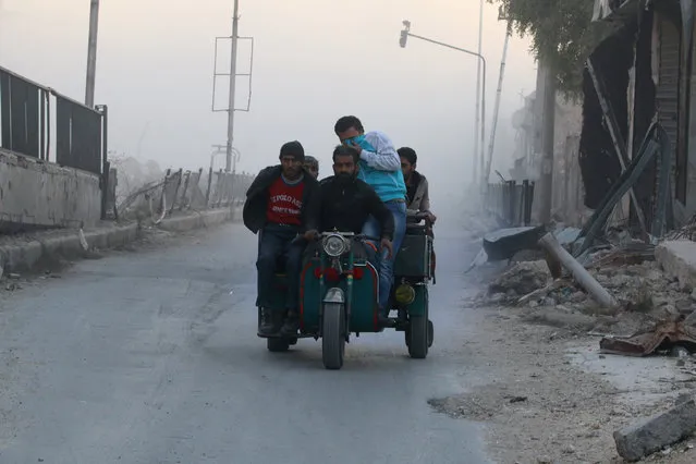 Men ride on a vehicle amidst dust after a strike on the rebel held besieged al-Shaar neighbourhood of Aleppo, Syria, November 26, 2016. (Photo by Abdalrhman Ismail/Reuters)
