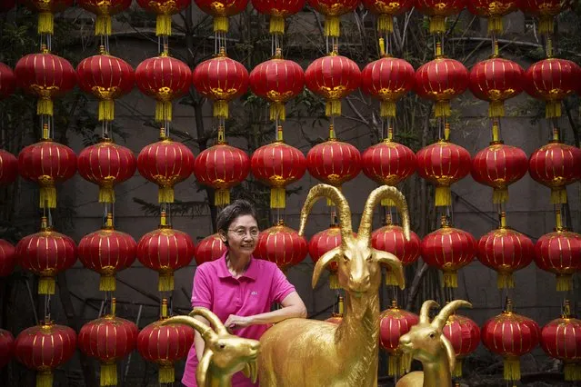 A woman stands behind statues of goats at the temple decorated for the Chinese Lunar New Year in Bangkok's Chinatown February 19, 2015. (Photo by Damir Sagolj/Reuters)