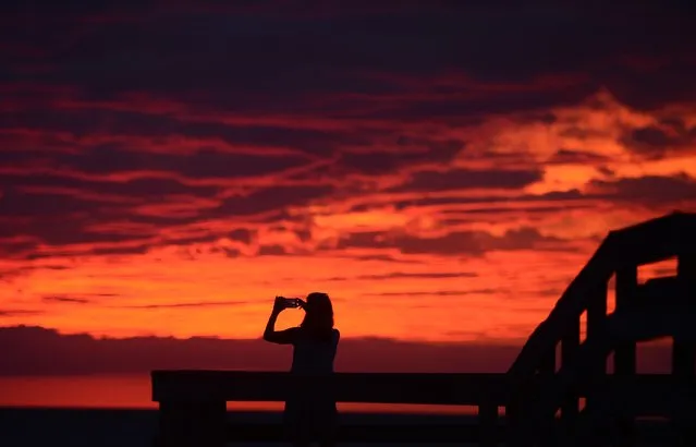 Karen Duer-Potts uses her cellphone to take a photograph of the sunset as the outer band of Hermine, which has weakened to a tropical storm, creeps over the beach at Cape Charles, Va., Friday, September 2, 2016. (Photo by Jay Diem/The Daily Times via AP Photo)