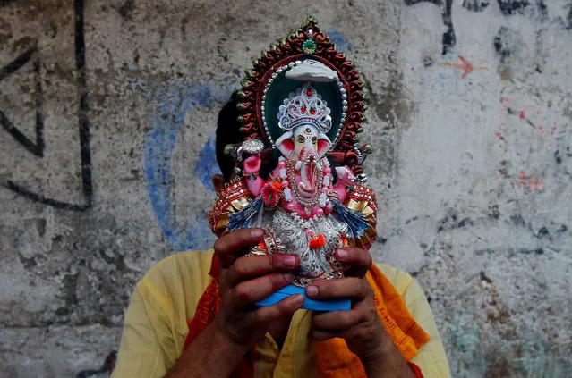 A Hindu priest prays as he holds an idol of the Hindu god Ganesh, the deity of prosperity, on the first day of the Bengali New Year inside a temple in Kolkata, India, April 15, 2018. (Photo by Rupak De Chowdhuri/Reuters)